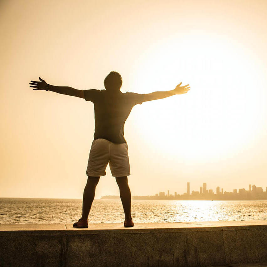  adult man standing on a ledge with his arms spread