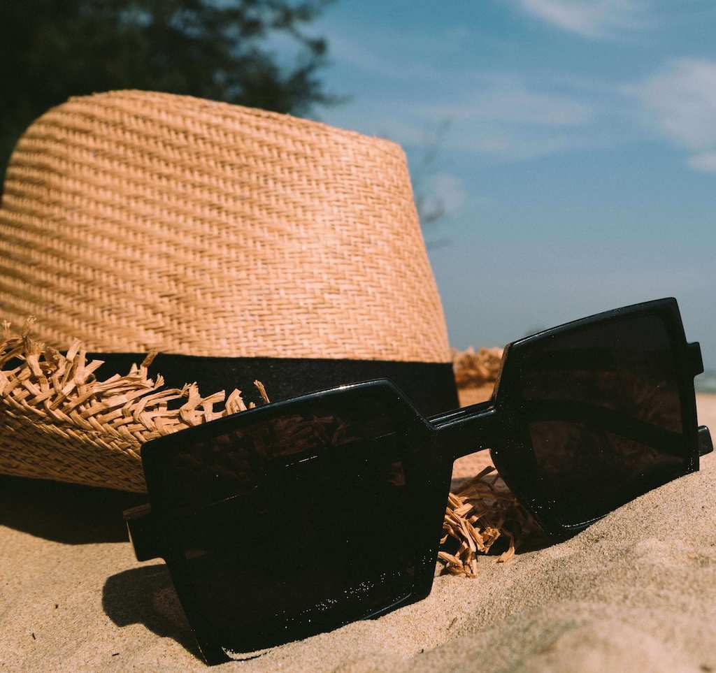 sun hat and sunglasses on sand